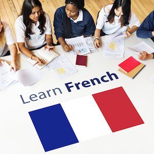 Students working together around a table with a French flag graphic reading Learn French